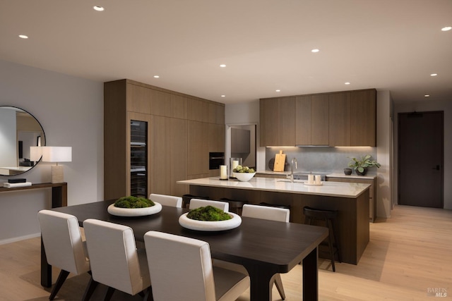 kitchen with light hardwood / wood-style floors, sink, and an island with sink