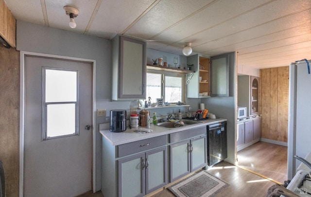 kitchen featuring hardwood / wood-style flooring, stainless steel dishwasher, gray cabinetry, and sink