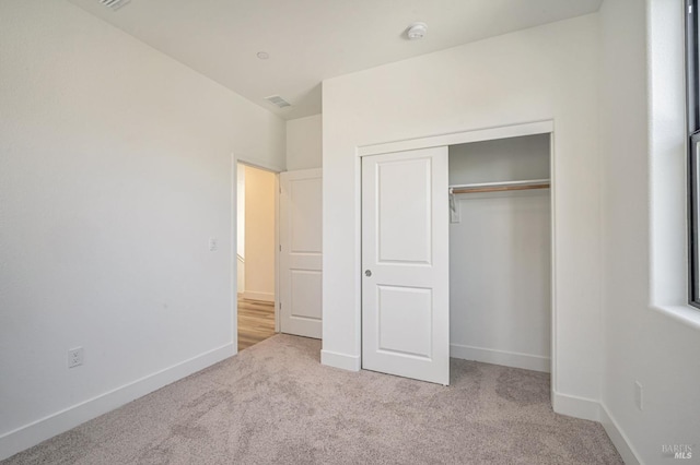 unfurnished bedroom featuring baseboards, carpet floors, a closet, and visible vents