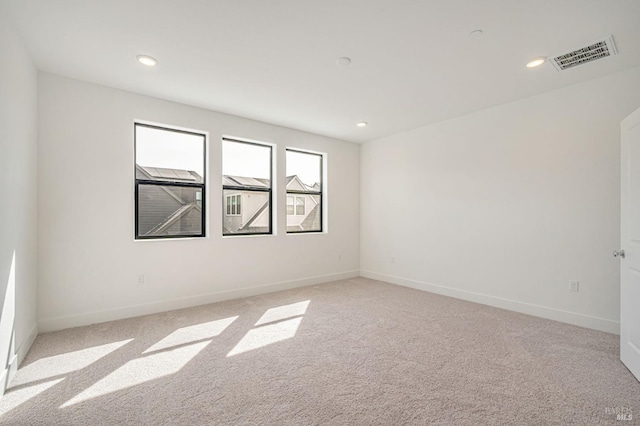 spare room featuring visible vents, baseboards, and light colored carpet