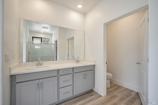 full bathroom featuring toilet, wood finished floors, a stall shower, and a sink