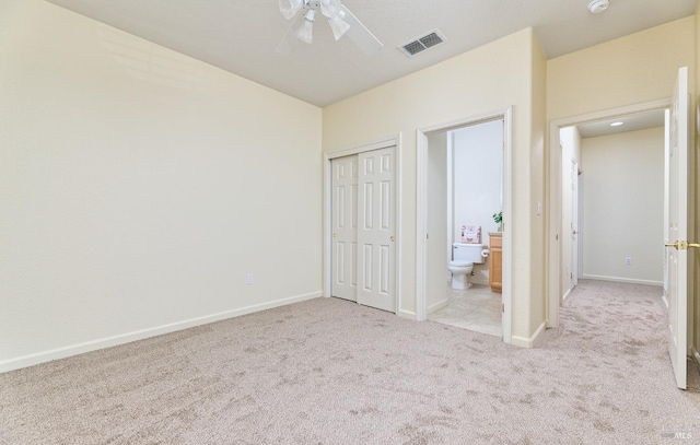 unfurnished bedroom with connected bathroom, a closet, light carpet, and ceiling fan