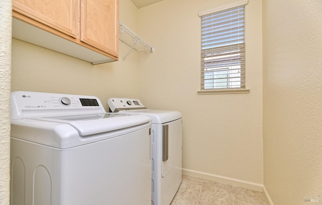 washroom featuring cabinets, light tile patterned flooring, and separate washer and dryer