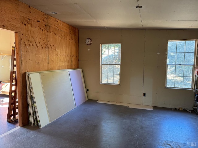 empty room with concrete flooring and wood walls