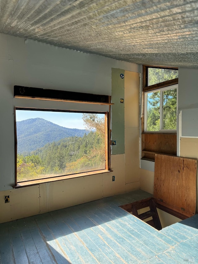 unfurnished bedroom with a mountain view, wood-type flooring, and lofted ceiling