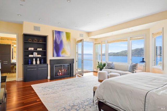 bedroom with a water and mountain view, access to outside, and dark hardwood / wood-style floors