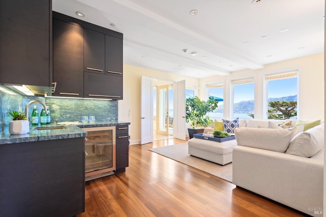 kitchen with wine cooler, beam ceiling, hardwood / wood-style floors, backsplash, and sink