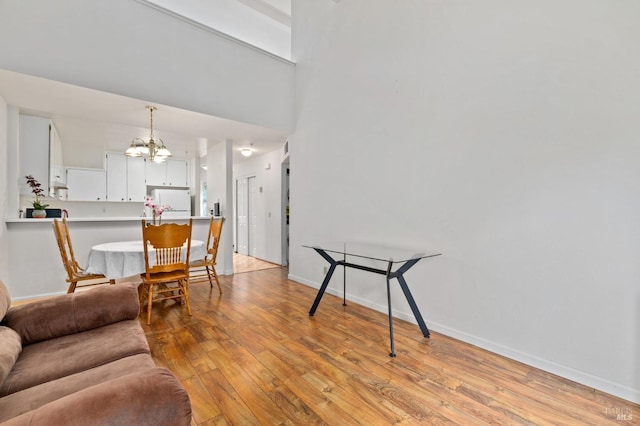 living room with light hardwood / wood-style flooring, a notable chandelier, and a high ceiling