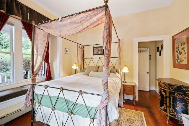 bedroom with a baseboard radiator, dark wood-style flooring, and multiple windows