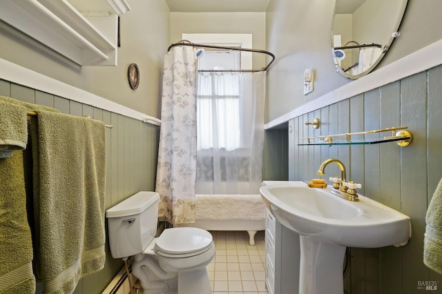 bathroom with a wainscoted wall, shower / tub combo, tile patterned flooring, and toilet