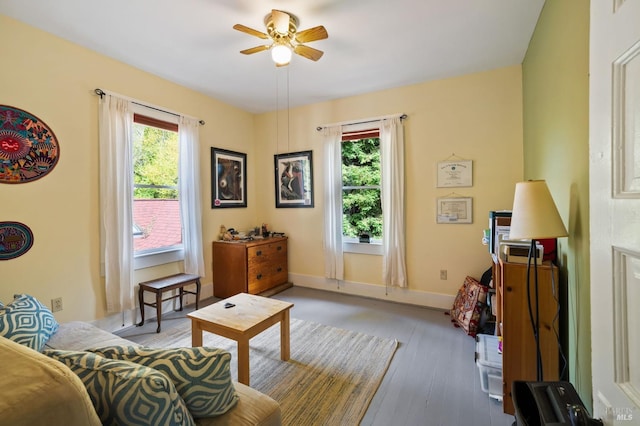 living area featuring light wood-style floors, ceiling fan, baseboards, and a wealth of natural light