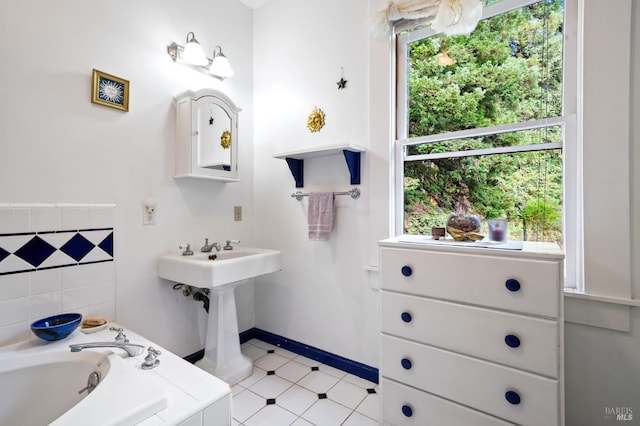 bathroom featuring baseboards, a bath, and tile patterned floors