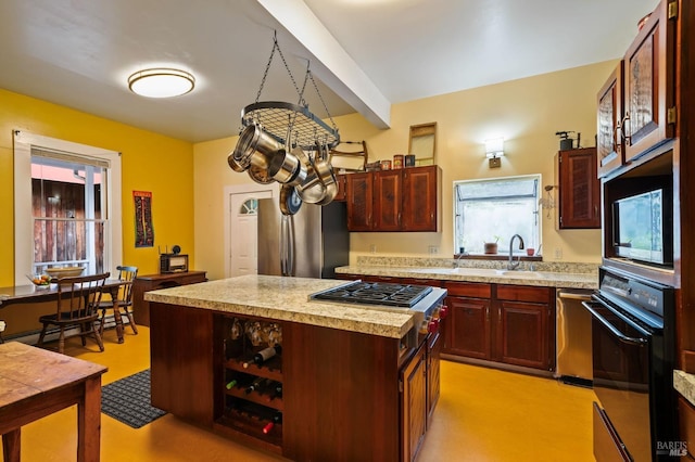 kitchen featuring a kitchen island, appliances with stainless steel finishes, light countertops, and a sink