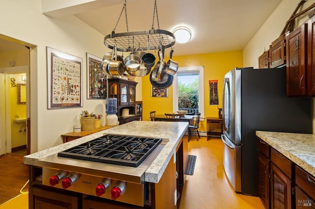 kitchen with light countertops, a kitchen island, freestanding refrigerator, and light wood-style floors