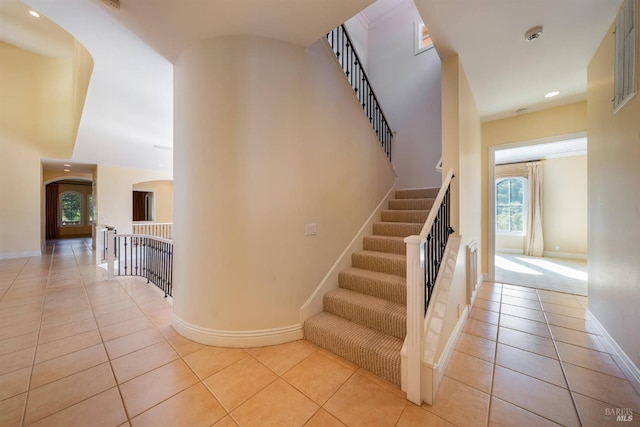 staircase featuring tile patterned flooring and a high ceiling