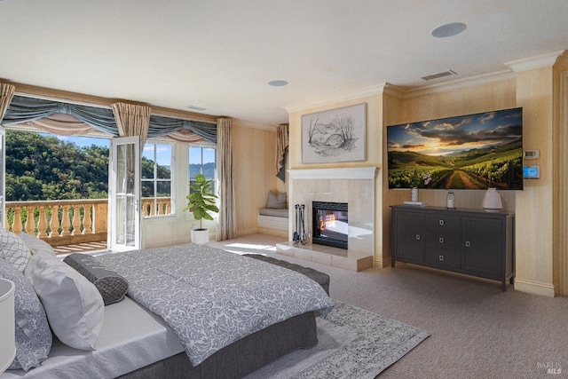 carpeted bedroom featuring a tile fireplace, crown molding, and access to exterior