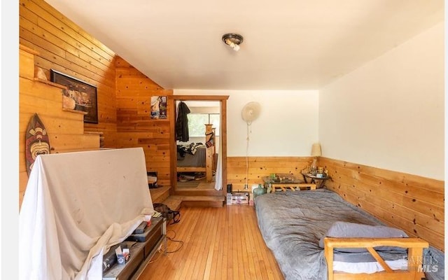 bedroom featuring light hardwood / wood-style floors and wooden walls