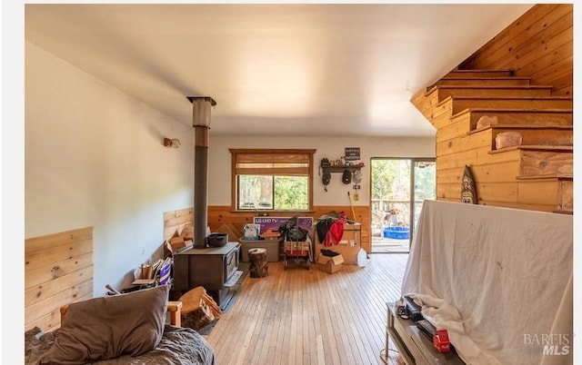 living room with hardwood / wood-style floors, a wood stove, and wooden walls