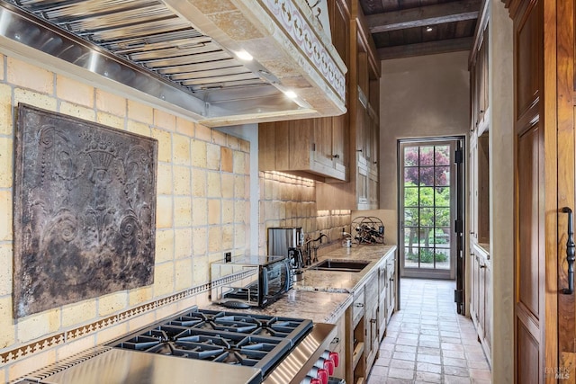 kitchen featuring light stone counters, sink, custom exhaust hood, and a high ceiling