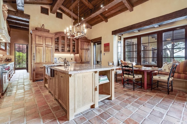 kitchen with high vaulted ceiling, beamed ceiling, plenty of natural light, and a center island with sink