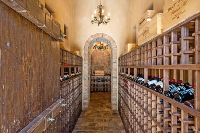 wine cellar featuring a towering ceiling and a notable chandelier