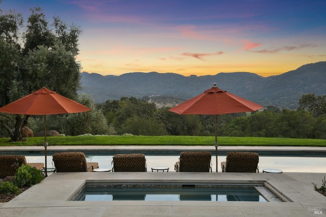 pool at dusk with a patio area and a mountain view