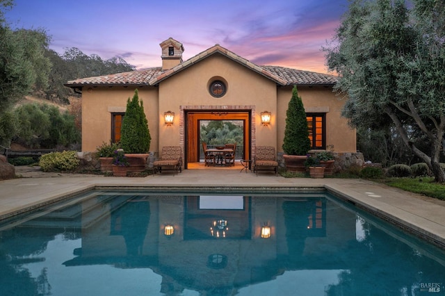 back house at dusk with a patio area