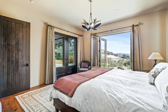 bedroom featuring access to outside, french doors, a notable chandelier, and dark wood-type flooring