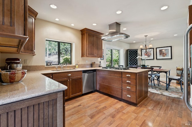 kitchen with island range hood, kitchen peninsula, stainless steel appliances, decorative light fixtures, and light wood-type flooring