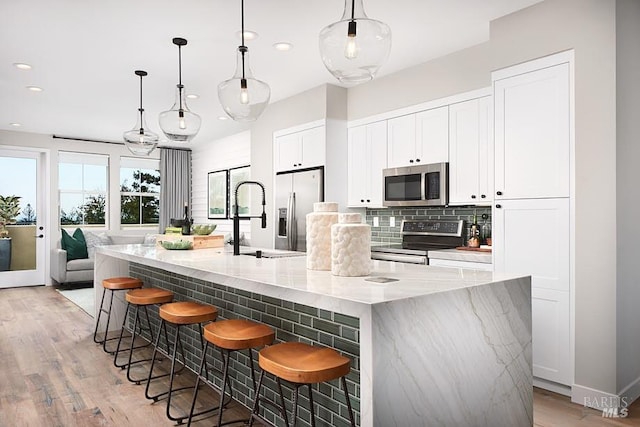 kitchen with a spacious island, hanging light fixtures, appliances with stainless steel finishes, and a kitchen bar