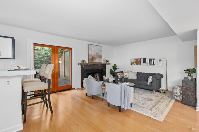 living area featuring a fireplace, french doors, and light wood-style floors
