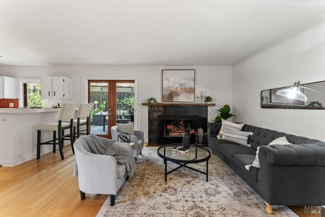 living area with a warm lit fireplace and light wood-style floors