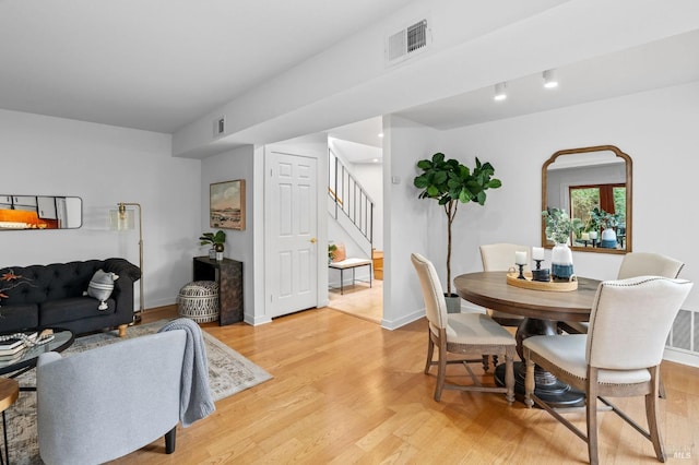 dining area with light wood-style flooring, baseboards, stairs, and visible vents