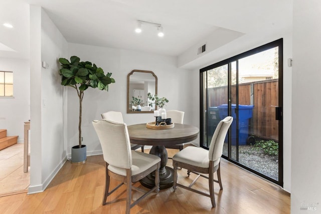 dining area with baseboards, visible vents, and light wood-style floors