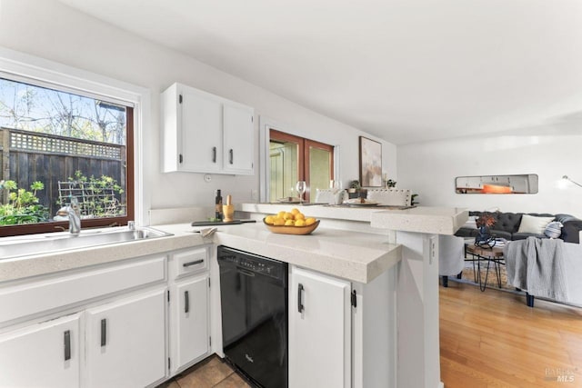 kitchen with open floor plan, light countertops, a sink, dishwasher, and a peninsula