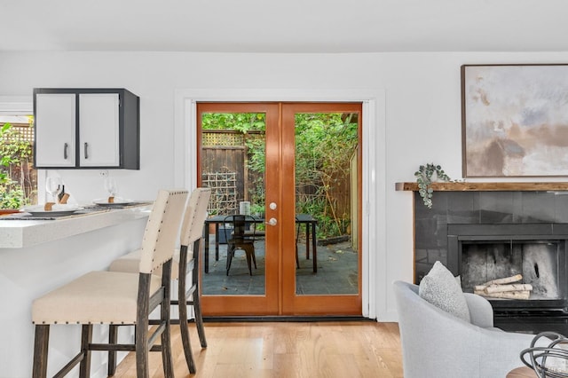 interior space with french doors, light hardwood / wood-style flooring, and a tiled fireplace