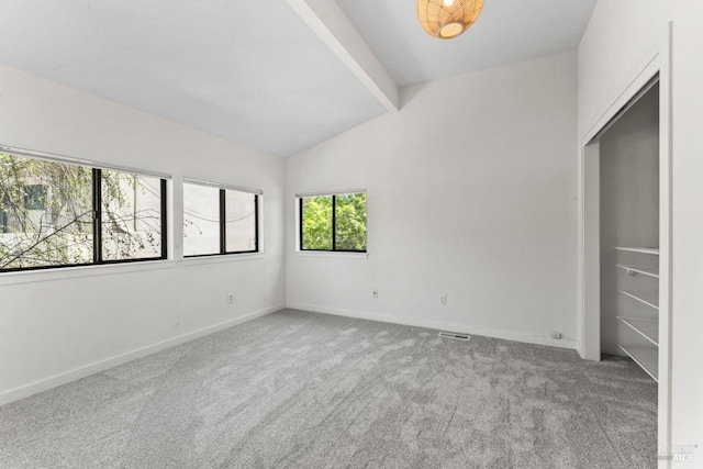 empty room featuring lofted ceiling with beams, baseboards, and carpet