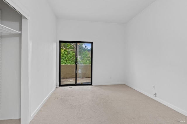 unfurnished bedroom with a closet, light carpet, and access to exterior