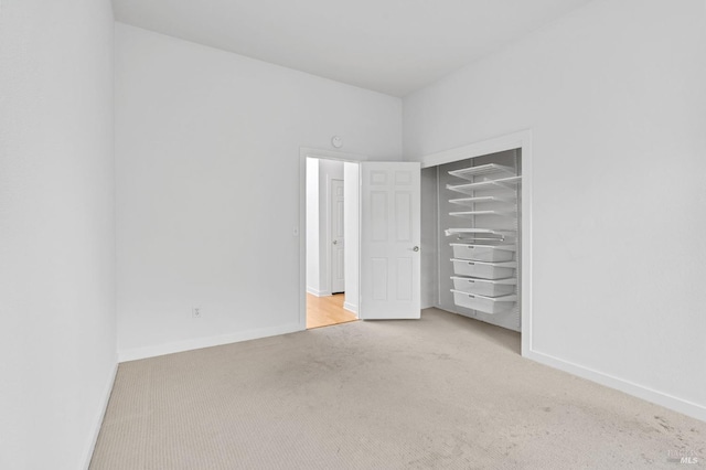 unfurnished bedroom featuring a closet and light colored carpet