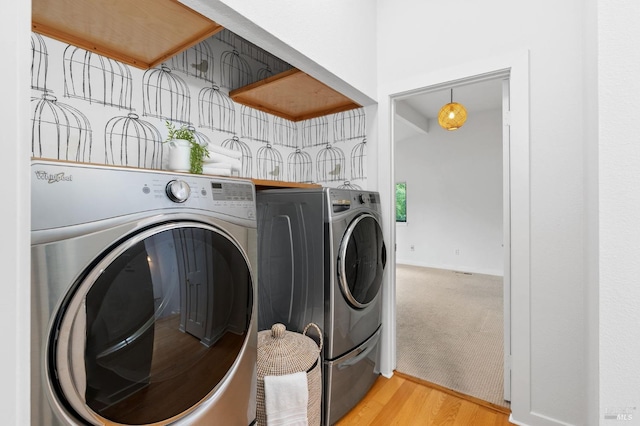 clothes washing area featuring washing machine and dryer and light wood-type flooring