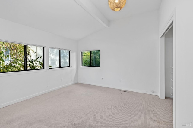 carpeted spare room featuring vaulted ceiling with beams