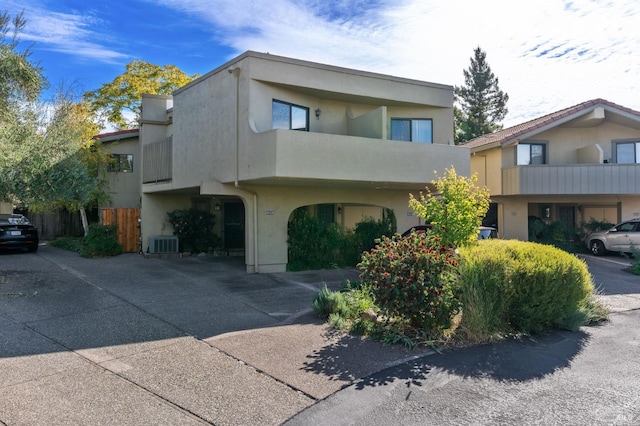 view of front of home with cooling unit, stucco siding, and fence