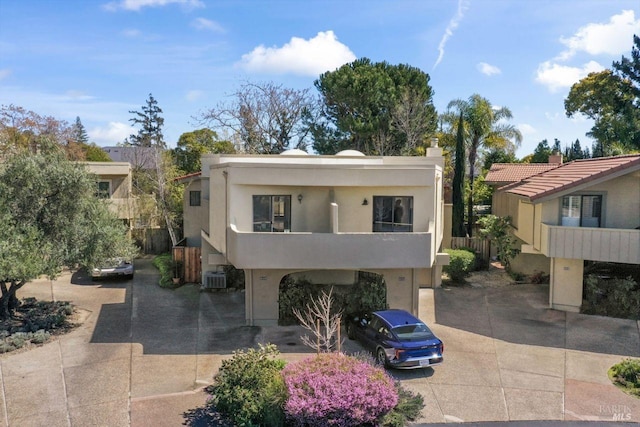 view of front of property featuring central air condition unit, stucco siding, and concrete driveway