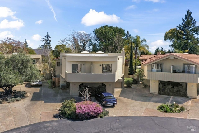 contemporary home featuring a balcony, driveway, an attached garage, a tile roof, and stucco siding