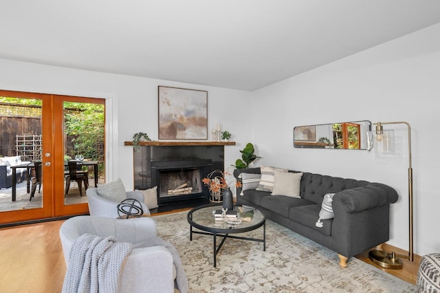 living room featuring french doors, a fireplace with flush hearth, and wood finished floors