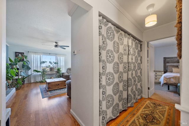 corridor featuring a textured ceiling, hardwood / wood-style floors, and crown molding