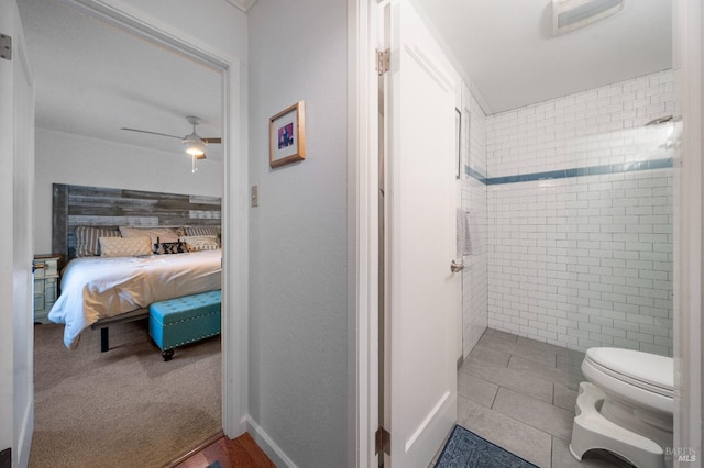 bathroom with toilet, ceiling fan, tile patterned floors, and tiled shower