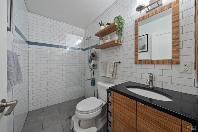 bathroom with tile walls, vanity, toilet, and a tile shower