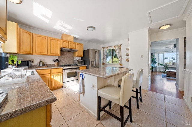 kitchen featuring stainless steel appliances, a breakfast bar area, light wood-type flooring, and ornamental molding