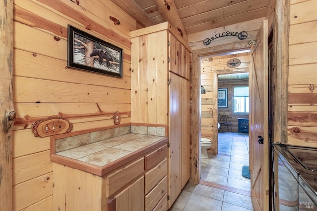 bathroom featuring tile patterned flooring, toilet, wood ceiling, and wooden walls